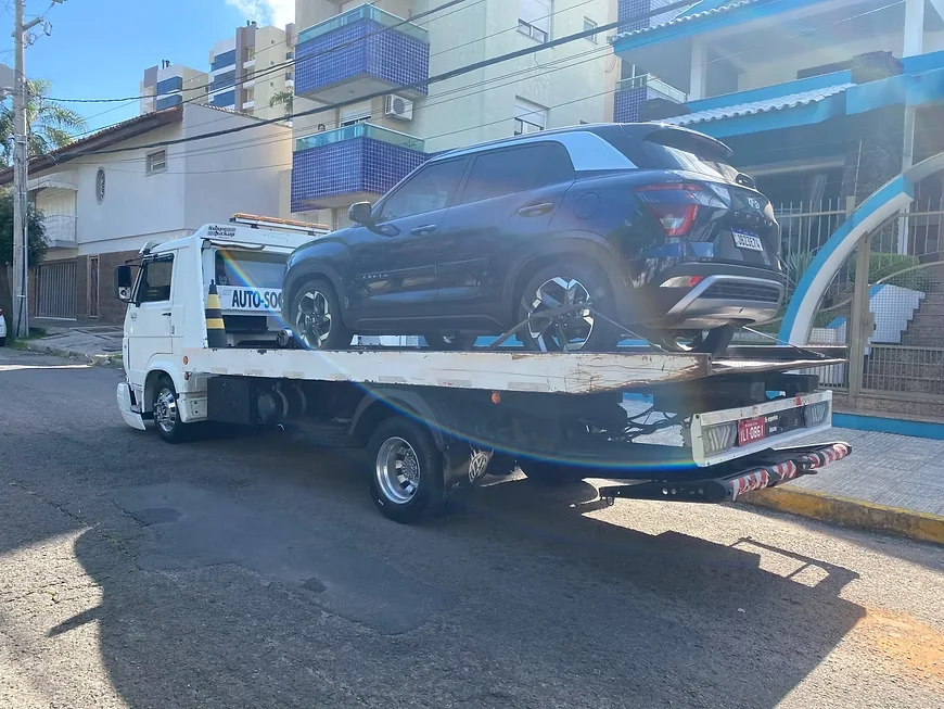SUV sendo transportado sobre a plataforma do guincho em via urbana