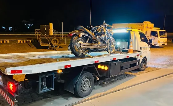 Motocicleta transportada na plataforma do guincho durante a noite