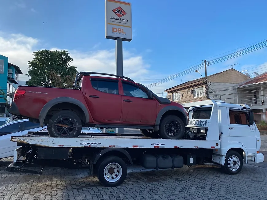 Picape vermelha sendo transportada pelo guincho durante o dia